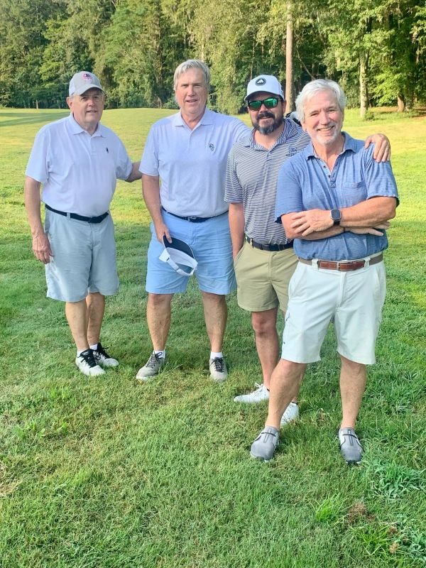 Four men posing on golf course fairway