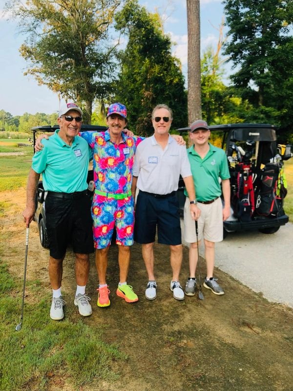 Foursome in colorful golf attire by carts