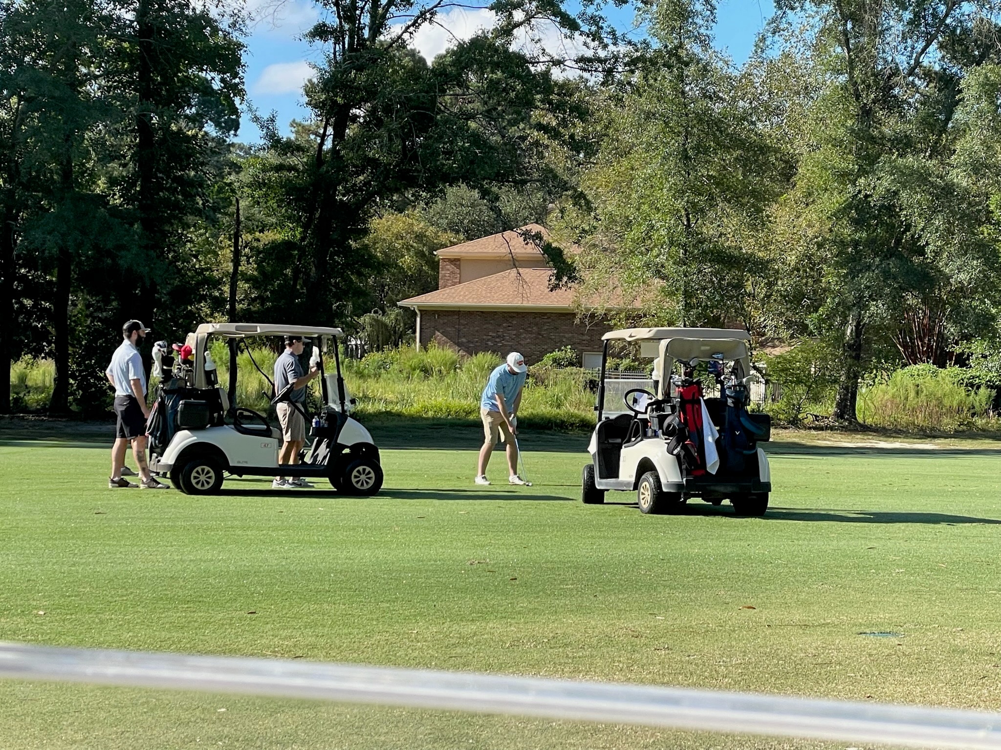 Golfers with carts on sunny fairway