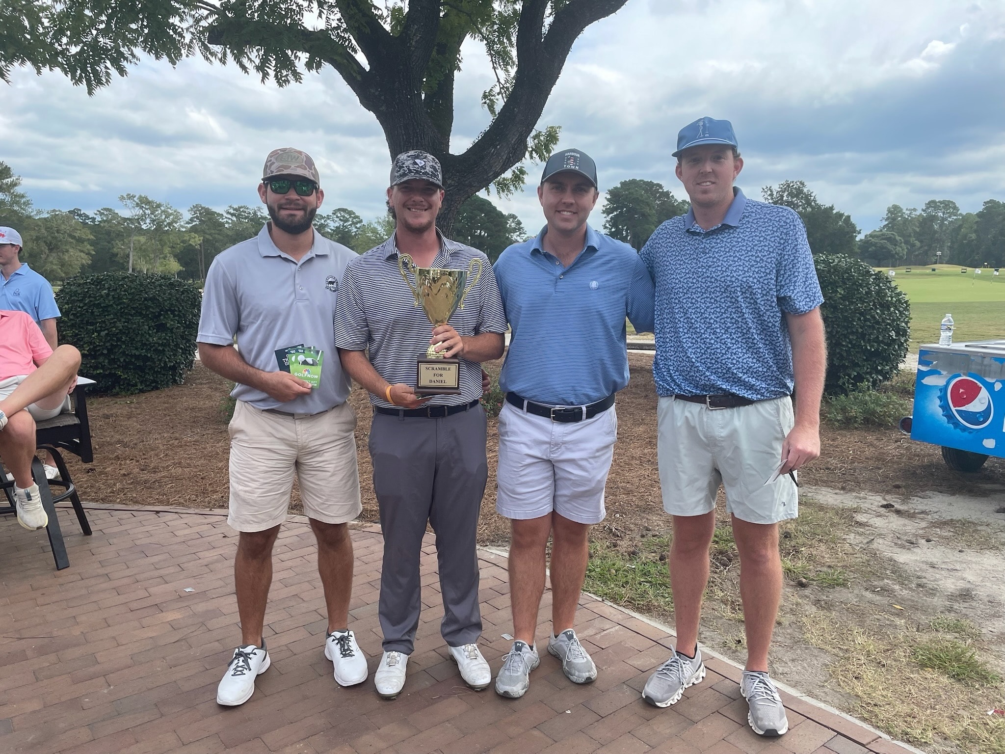 Four golfers holding the Scramble for Daniel trophy